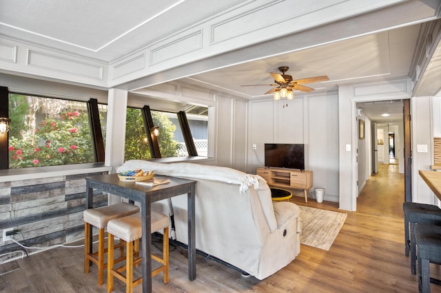 living room with ceiling fan, a decorative wall, and wood finished floors