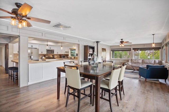 dining area featuring light wood-style floors, visible vents, and a ceiling fan