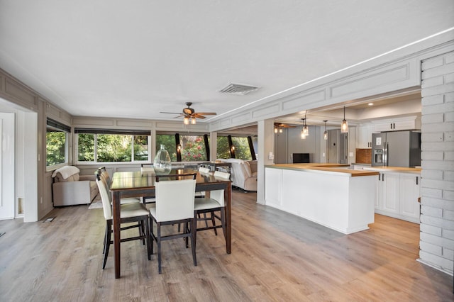 dining space featuring ceiling fan, light wood finished floors, and visible vents