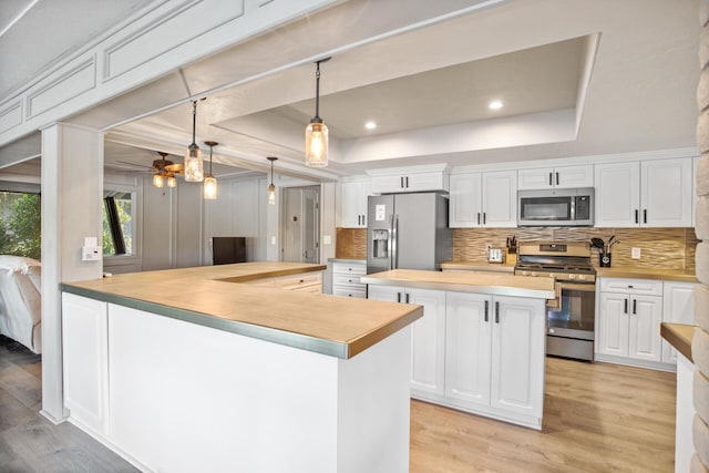 kitchen with stainless steel appliances, a raised ceiling, white cabinets, and a kitchen island