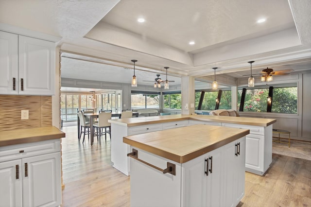 kitchen with hanging light fixtures, a tray ceiling, white cabinetry, and a center island