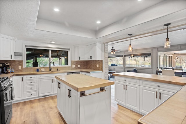 kitchen with a kitchen island, black range with gas stovetop, a sink, and white cabinetry