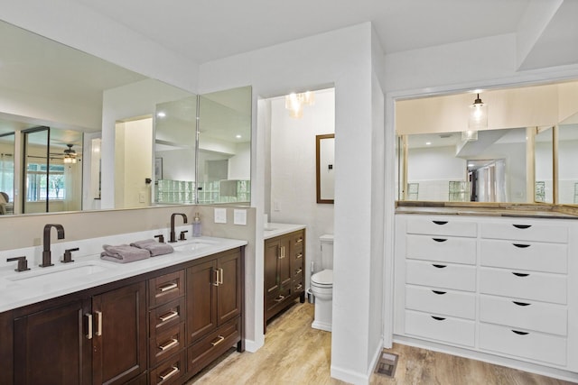 full bath featuring double vanity, toilet, a sink, and wood finished floors