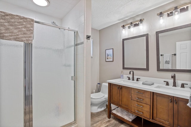 bathroom featuring toilet, a shower stall, a sink, and wood finished floors