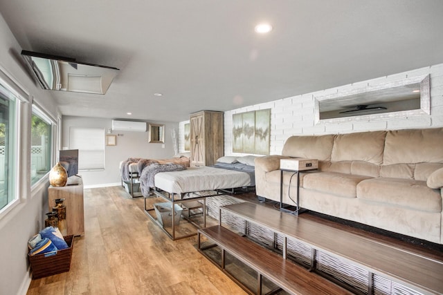 bedroom with light wood-type flooring, an AC wall unit, baseboards, and recessed lighting