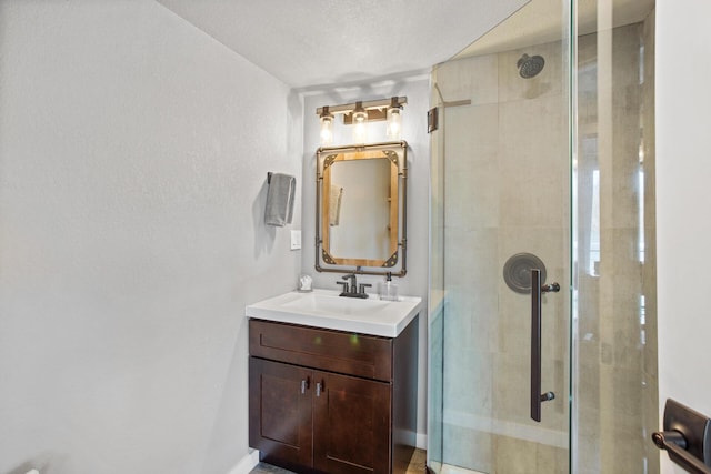 full bathroom featuring a shower stall, a textured ceiling, and vanity