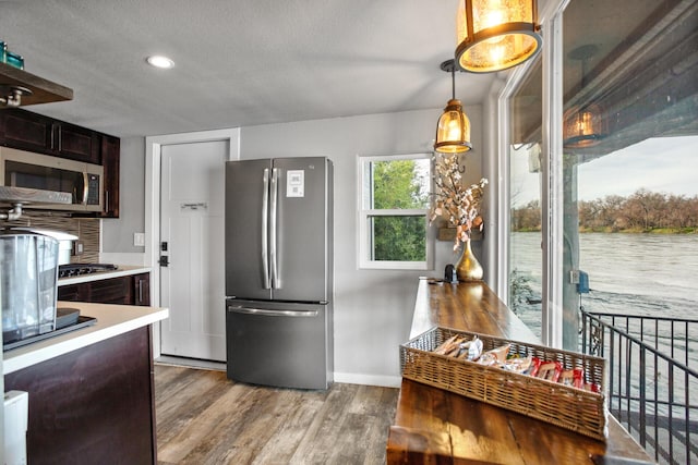 kitchen with light countertops, appliances with stainless steel finishes, dark brown cabinetry, a textured ceiling, and light wood-type flooring