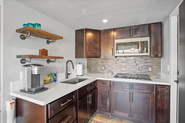 kitchen featuring tasteful backsplash, appliances with stainless steel finishes, light countertops, and a sink