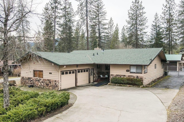 single story home featuring a garage, concrete driveway, roof with shingles, and stone siding