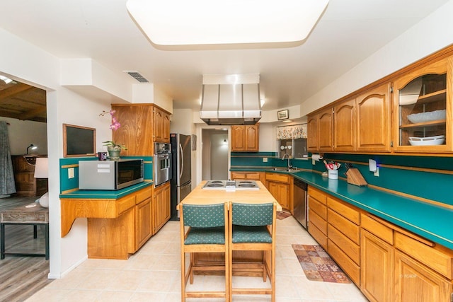 kitchen with visible vents, a kitchen island, glass insert cabinets, stainless steel appliances, and a sink