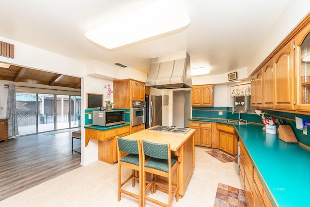 kitchen featuring stainless steel appliances, dark countertops, visible vents, a sink, and island range hood