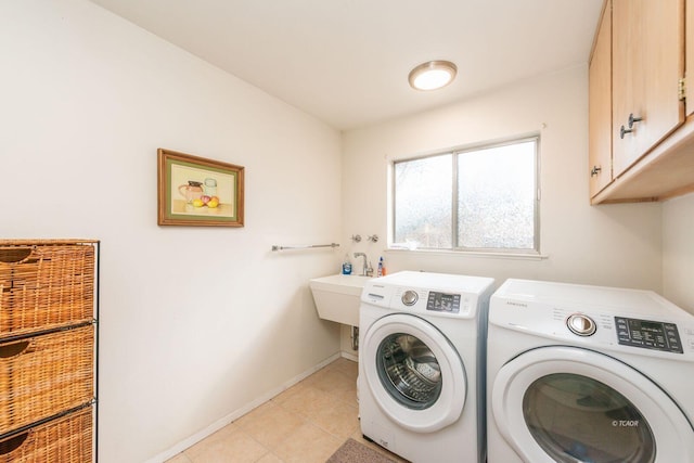 washroom with light tile patterned floors, washing machine and dryer, a sink, baseboards, and cabinet space