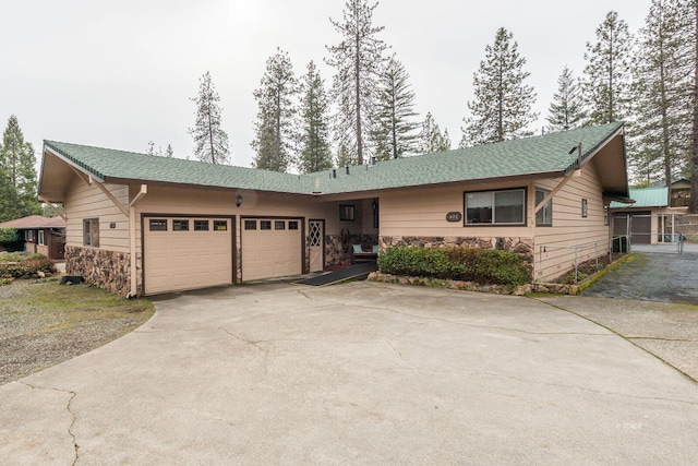 ranch-style house featuring driveway, stone siding, and an attached garage