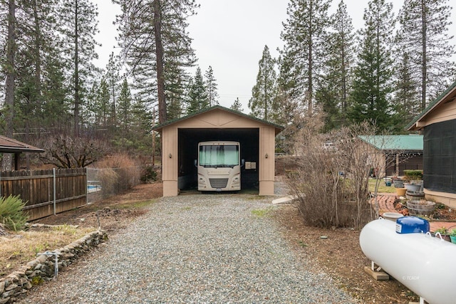 view of outdoor structure with an outbuilding, fence, and driveway