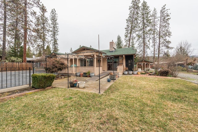 rear view of property with a chimney, a gazebo, fence, a yard, and a patio area