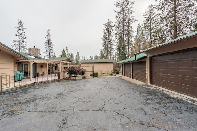 exterior space with a garage, driveway, fence, and an outdoor structure