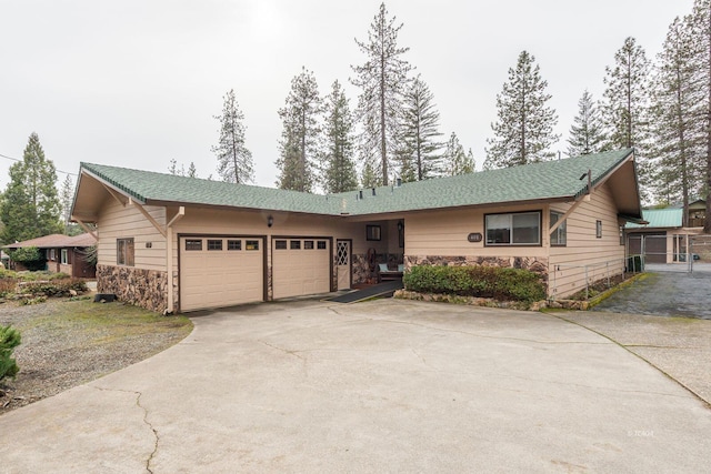 single story home featuring a garage, driveway, and stone siding