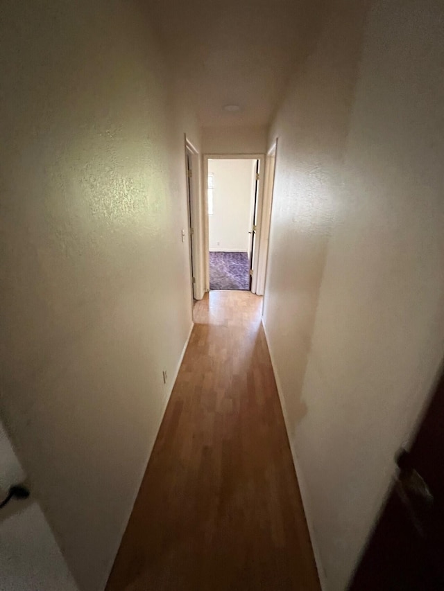 corridor with wood finished floors and baseboards