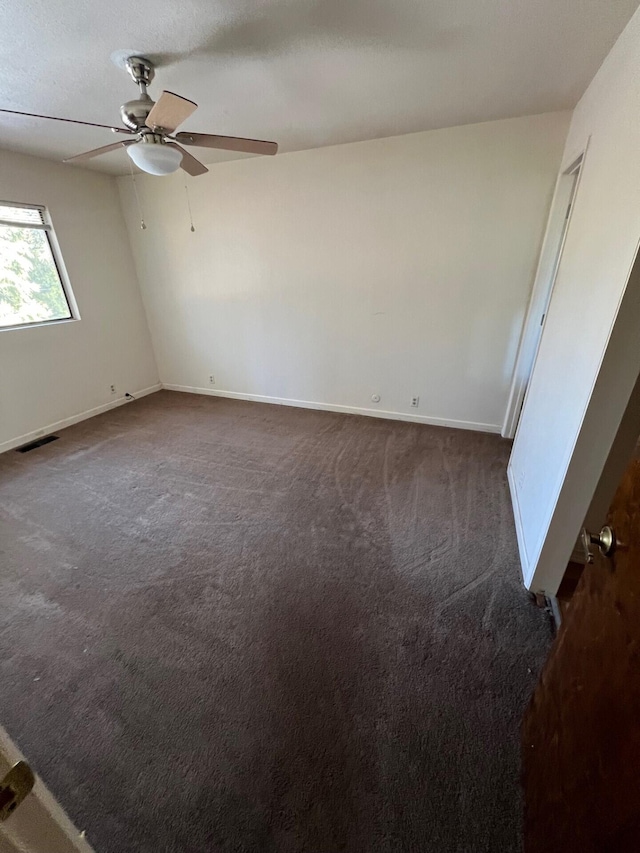 unfurnished bedroom with baseboards, visible vents, dark carpet, and a ceiling fan