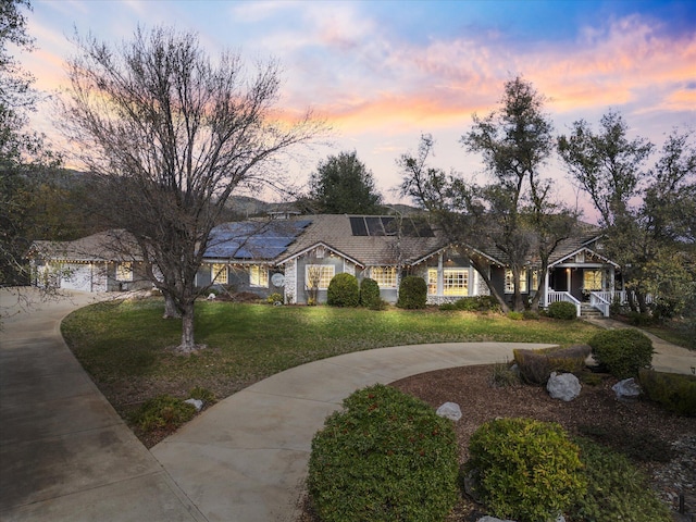 view of front of home featuring covered porch, roof mounted solar panels, a front lawn, and concrete driveway