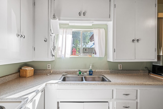 kitchen with light countertops, a sink, and white cabinets