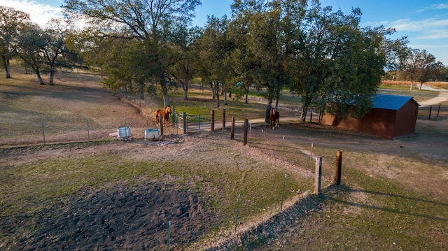 view of yard featuring a rural view, fence, and an outdoor structure