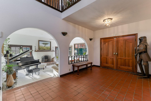 foyer entrance with plenty of natural light, a glass covered fireplace, tile patterned flooring, and baseboards