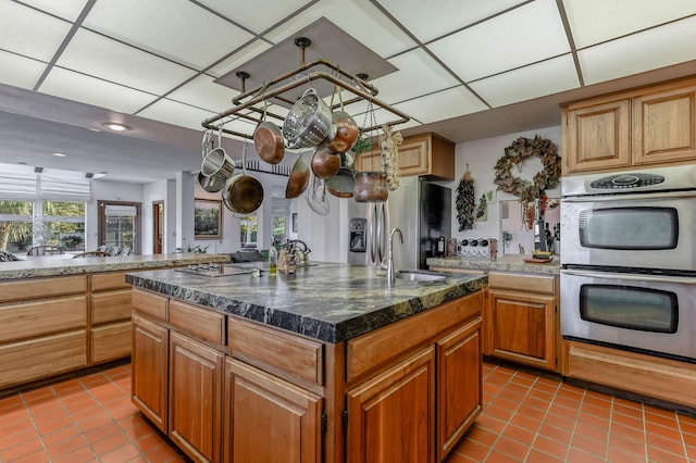 kitchen featuring a sink, plenty of natural light, a center island with sink, and stainless steel double oven