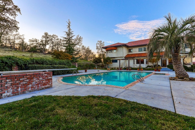 pool with a yard and a patio