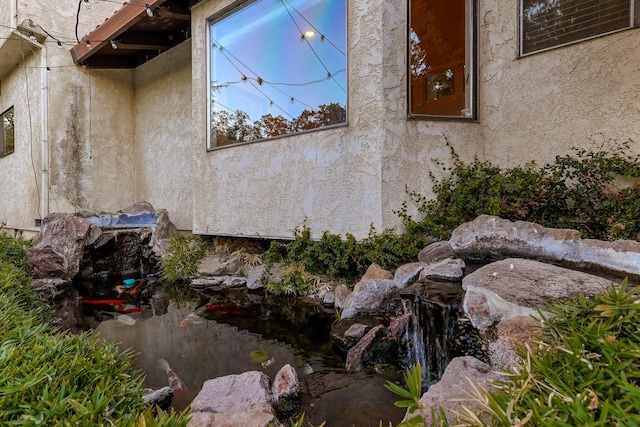 view of home's exterior featuring a small pond and stucco siding