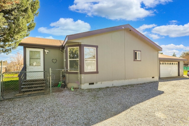 view of property exterior with gravel driveway, an attached garage, crawl space, a gate, and fence