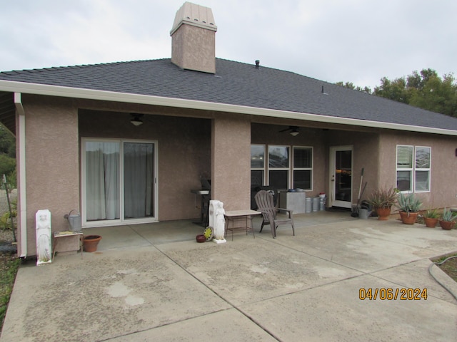 back of house featuring a patio, roof with shingles, a chimney, and stucco siding