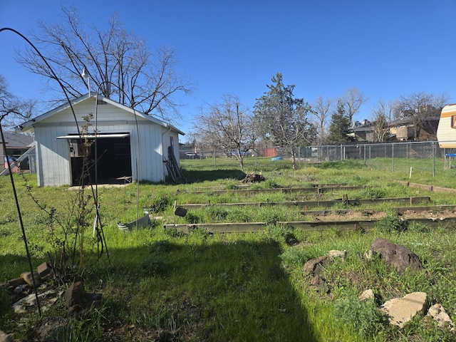 view of yard with a garden, a detached garage, and fence