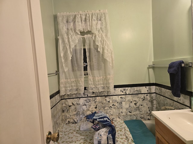 bathroom with a wainscoted wall, vanity, and tile walls