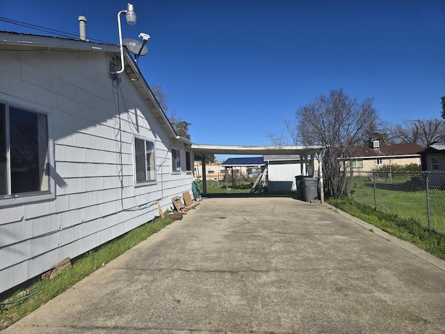 view of side of property featuring a carport, fence, and driveway