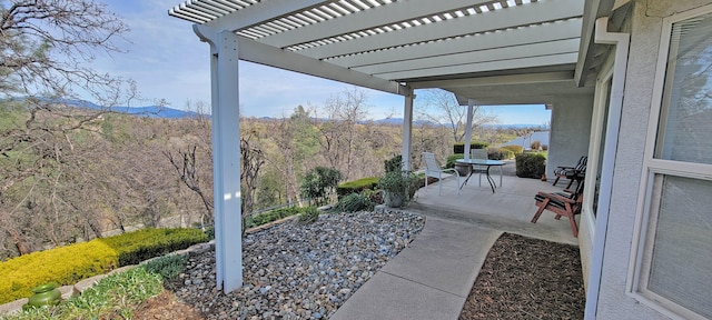 view of patio / terrace with a view of trees and a pergola