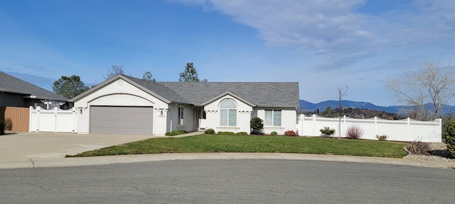 single story home with a mountain view, a garage, fence, concrete driveway, and a front lawn