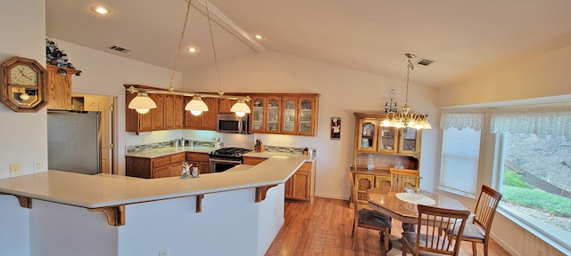 kitchen with lofted ceiling, stainless steel appliances, brown cabinetry, and a kitchen bar