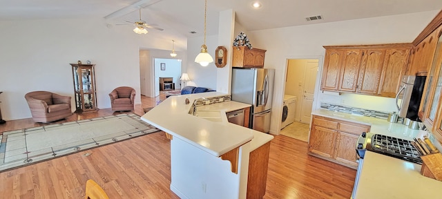 kitchen with a peninsula, a sink, open floor plan, light countertops, and appliances with stainless steel finishes