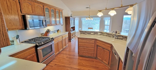 kitchen featuring stainless steel appliances, a sink, light countertops, and brown cabinets