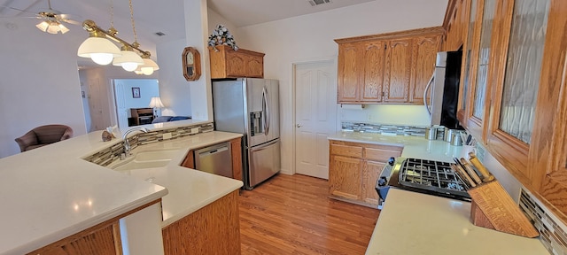 kitchen featuring stainless steel appliances, visible vents, light countertops, light wood finished floors, and decorative light fixtures