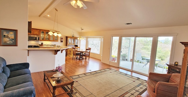 living area with a wealth of natural light, beam ceiling, visible vents, and light wood-style flooring