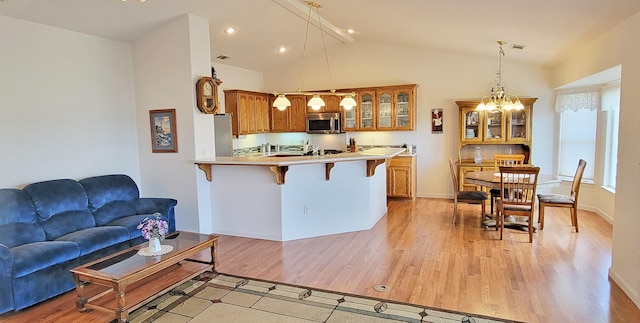 kitchen featuring stainless steel appliances, a peninsula, a kitchen bar, and brown cabinets