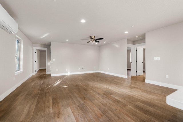 unfurnished room featuring recessed lighting, a wall unit AC, baseboards, and wood finished floors