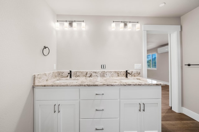 bathroom with wood finished floors, a sink, baseboards, and a wall mounted AC