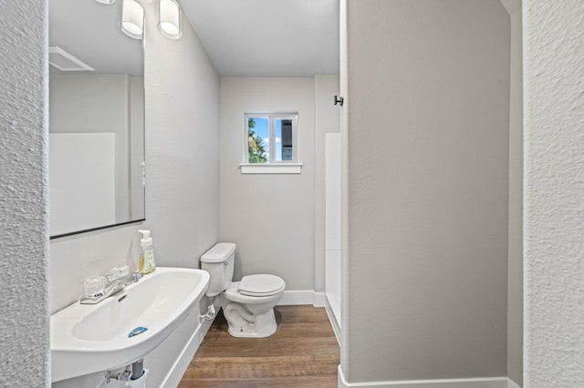 bathroom with baseboards, a textured wall, toilet, wood finished floors, and a sink