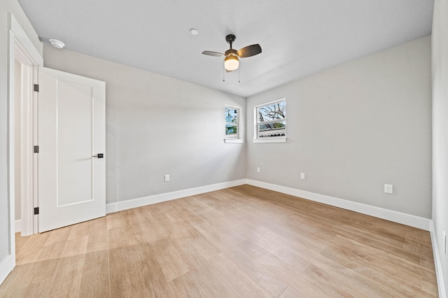 spare room featuring a ceiling fan, light wood-type flooring, and baseboards