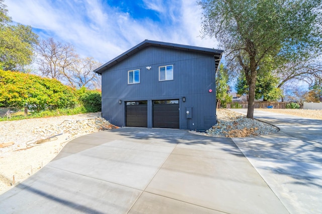 view of property exterior featuring concrete driveway, fence, and an attached garage