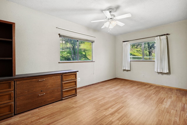 spare room featuring baseboards, light wood-type flooring, and a textured ceiling