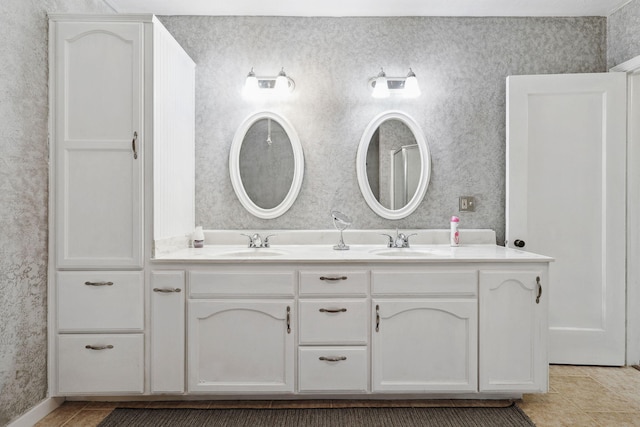 bathroom with a sink, tile patterned floors, double vanity, and wallpapered walls